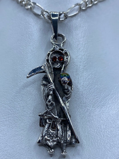 Primer plano del rostro de la Santa Muerte con circonia roja engastada, detalle de la guadaña
