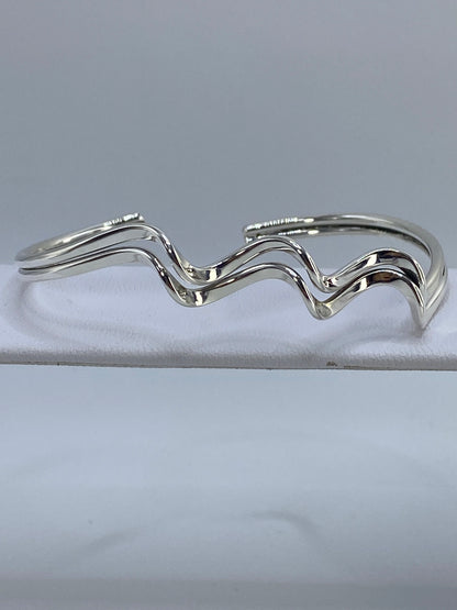 Brazalete rígido de plata 925 en cartoneado visto de arriba sobre fondo blanco