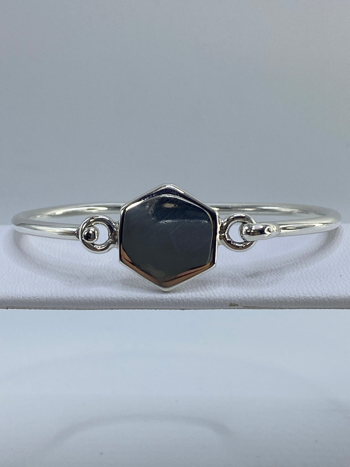 Brazalete cartoneado de plata 925 sobre fondo blanco, vista frontal mostrando el hexágono geométrico