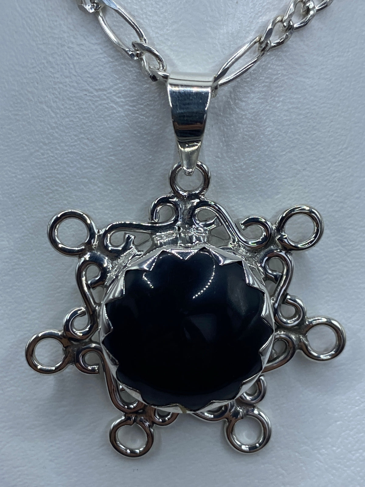 Detalle frontal del dije mostrando el ónix negro brillante y los anillos filigranados
