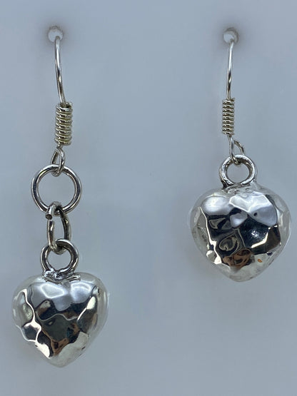 Detalle de escala: aretes de corazón de 3.8 cm junto a regla de centímetros