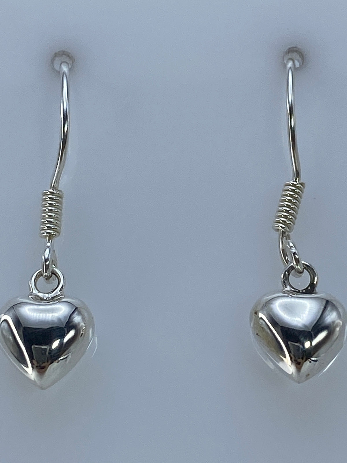 Aretes de plata 925 en gancho colgando sobre fondo blanco