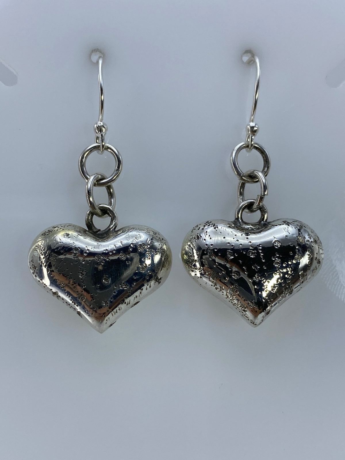 Detalle lateral de arete de corazón en plata con volumen 3D, cartoneado de Taxco