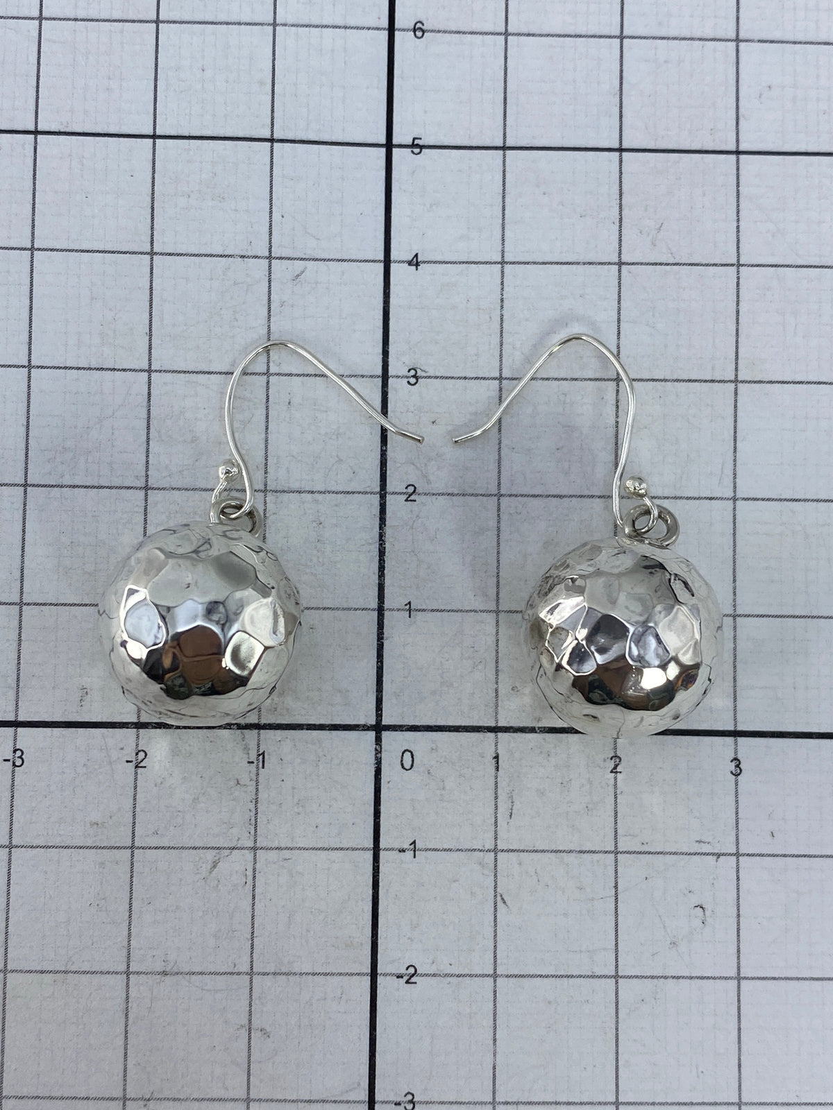 Aretes de plata cartoneado en la mano, mostrando ligereza y brillo
