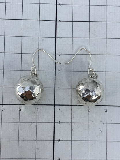 Aretes de plata cartoneado en la mano, mostrando ligereza y brillo