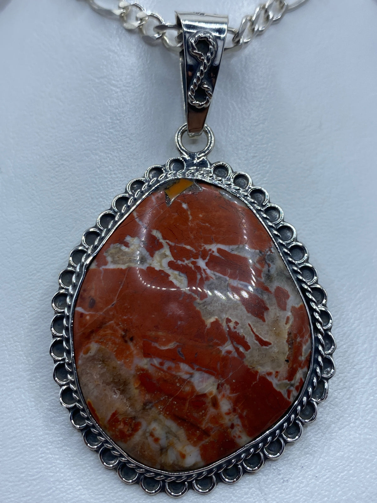 Dije de plata 950 con piedra café natural engastada, colgado de cadena plateada