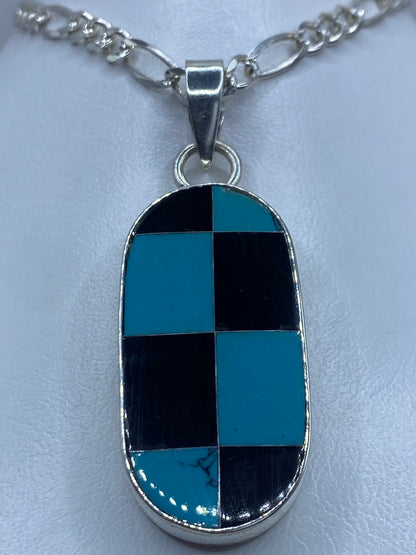 Dije de plata en patrón tablero con turquesa azul cielo y ónix negro engastado a mano