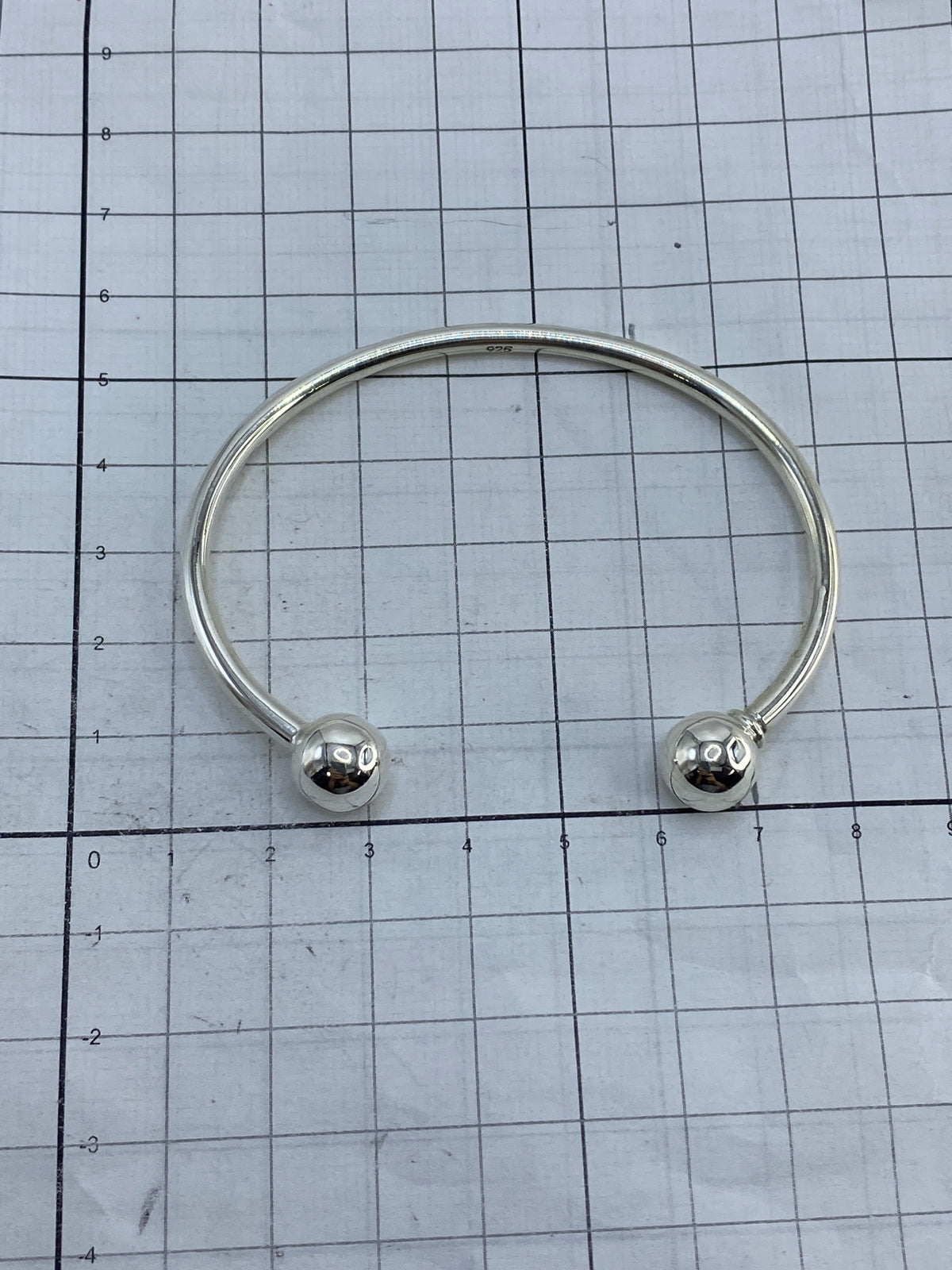 Brazalete rígido de plata sobre fondo blanco con el Quinto 925 visible