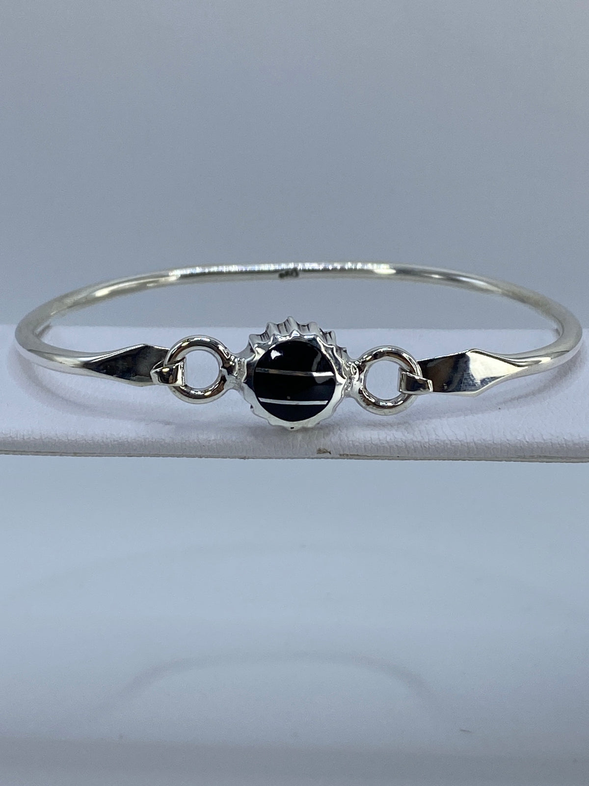 Brazalete rígido de plata 950 con ónix negro engastado en el centro, vista frontal