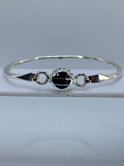 Brazalete rígido de plata 950 con ónix negro engastado en el centro, vista frontal