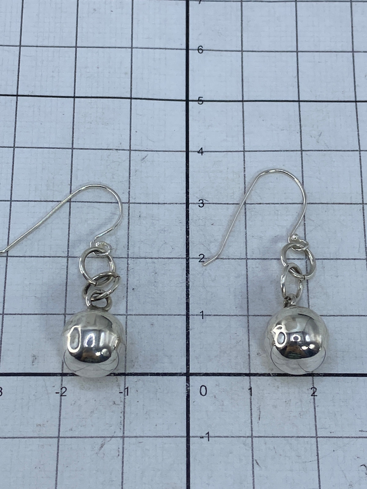 Aretes de plata cartoneada brillante sobre fondo blanco