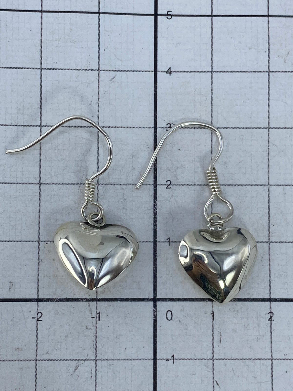 Aretes sobre fondo gris con escala de medida, mostrando el Quinto 925