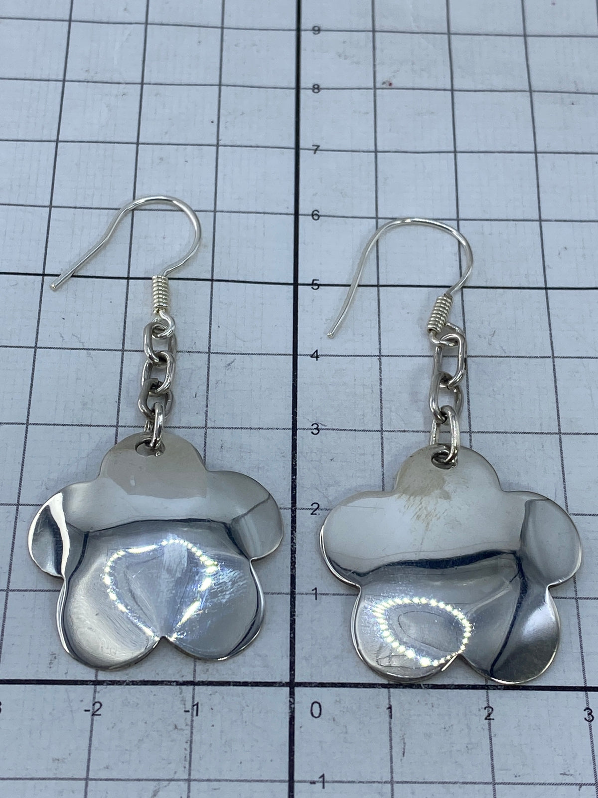 Aretes colgando, mostrando el cierre francés en plata y el brillo pulido