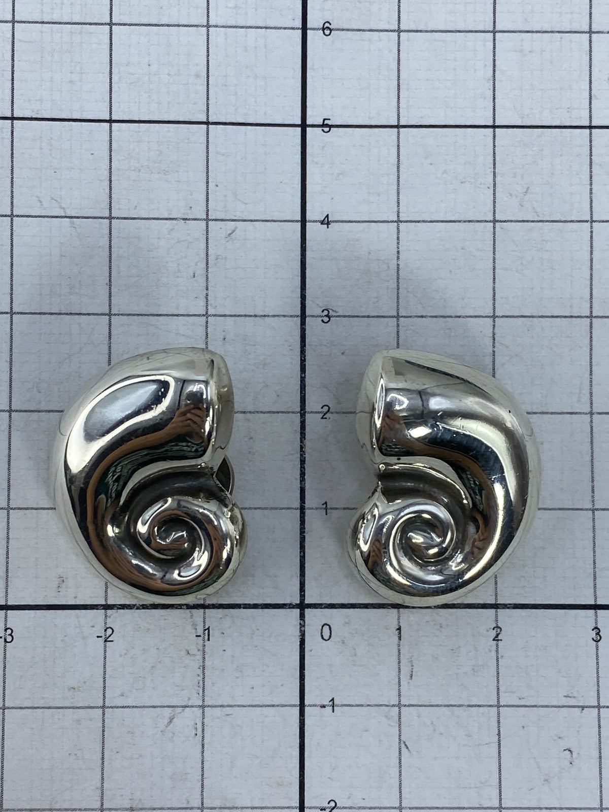 Aretes de plata sobre fondo blanco, vista frontal