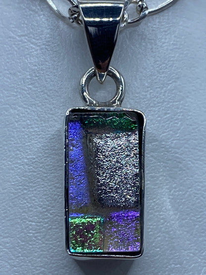 Dije de 3.9 cm en la mano, sobre cadena plateada