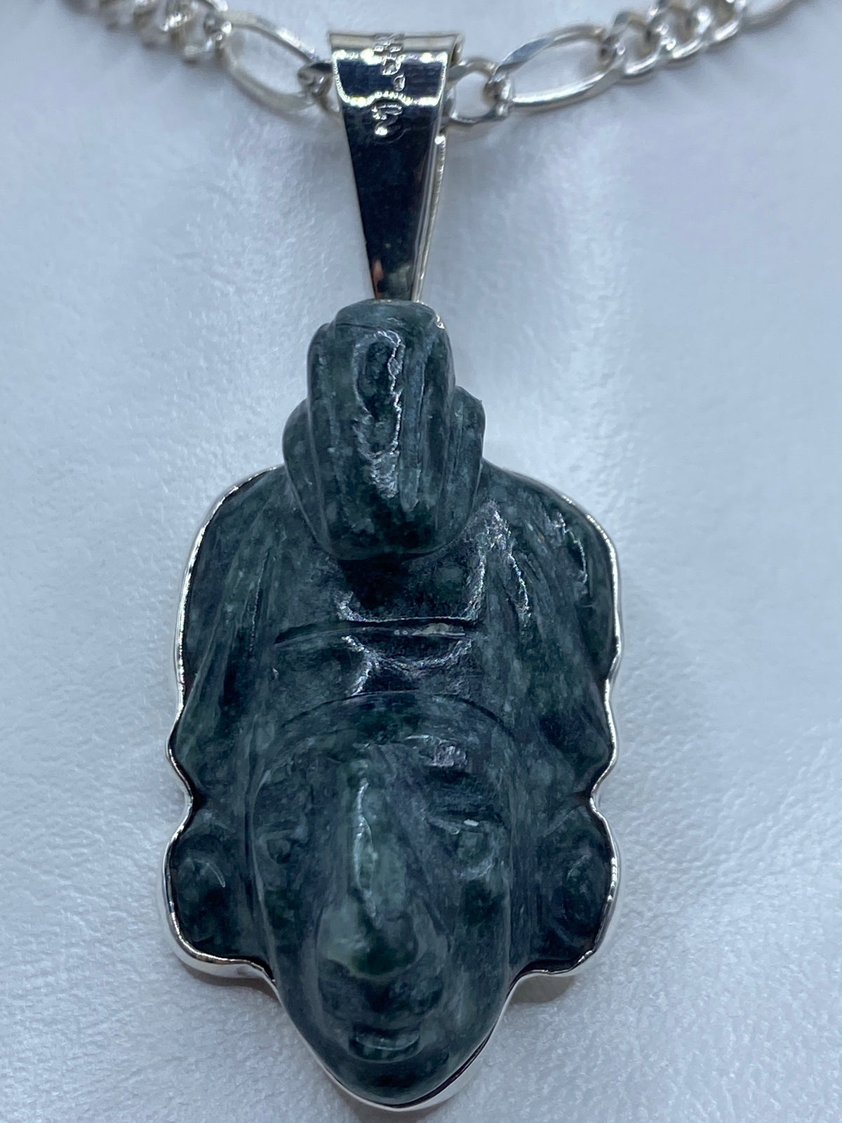 Dije de plata repujado con rostro de K'inich Janaab' Pakal y piedra verde, colgando de cadena de plata