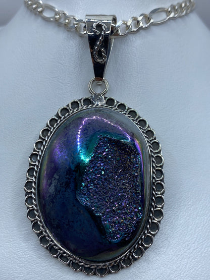 Dije ovalado de plata 925 con piedra morada engastada, marco calado de Taxco, colgando de cadena plateada