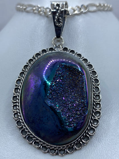 Detalle frontal del dije de piedra morada mostrando el engaste a mano y el marco calado