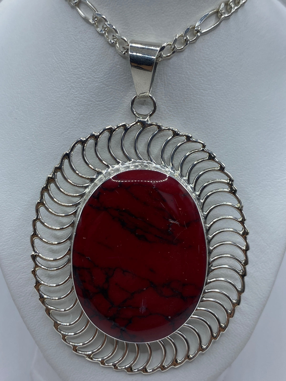 Detalle del coral rojo intenso y el marco ondulante de plata de Taxco