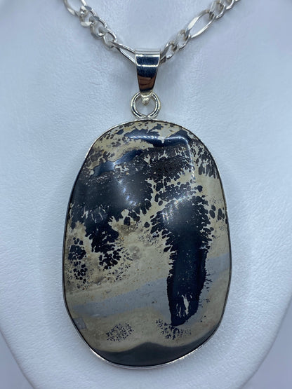 Dije de plata 925 con piedra natural moteada de azul y crema, engastada a mano, colgando de cadena de plata