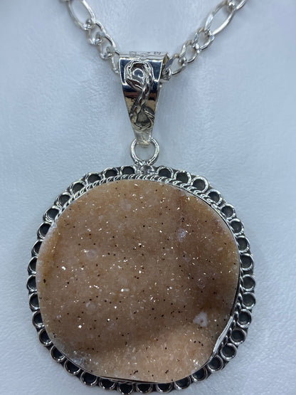Detalle frontal de la drusa de cuarzo con cristales brillantes enmarcados en plata pulida