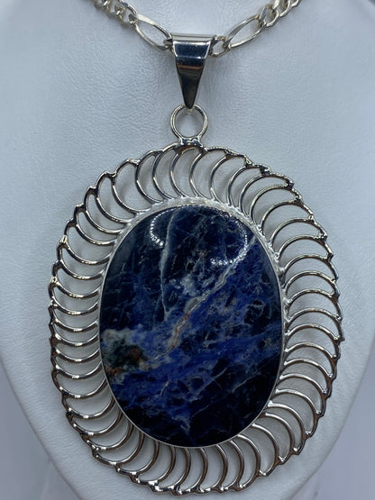 Dije ovalado de plata 950 con lapislázuli azul profundo y marco ornamental de Taxco