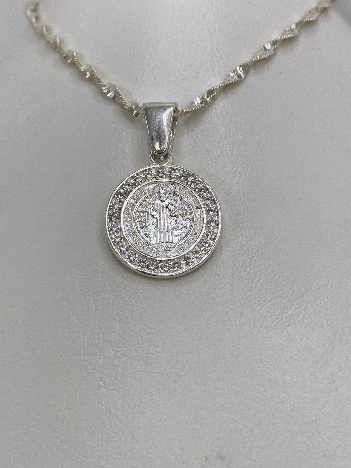 Detalle frontal de la Medalla San Benito grabada con leyenda protectora en plata de Taxco