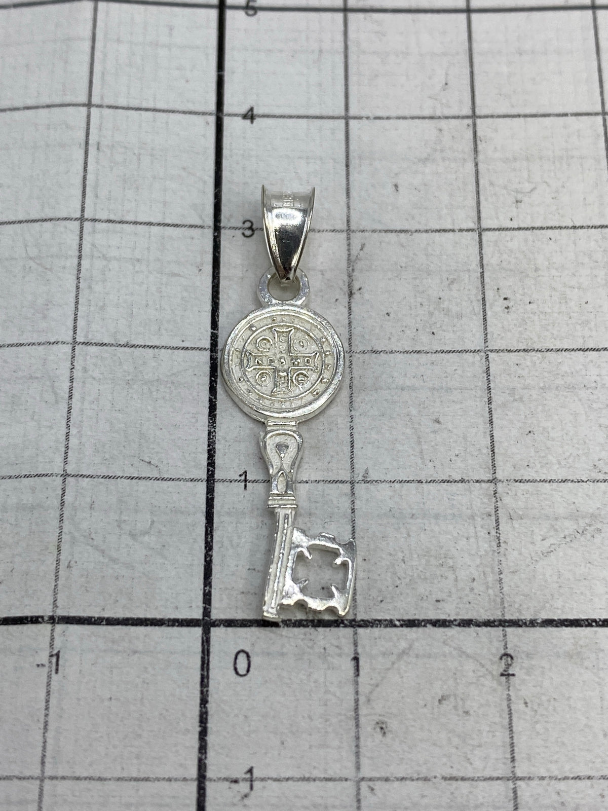 Dije Medal de San Benito sobre rejilla de medición mostrando 3.2 cm de largo