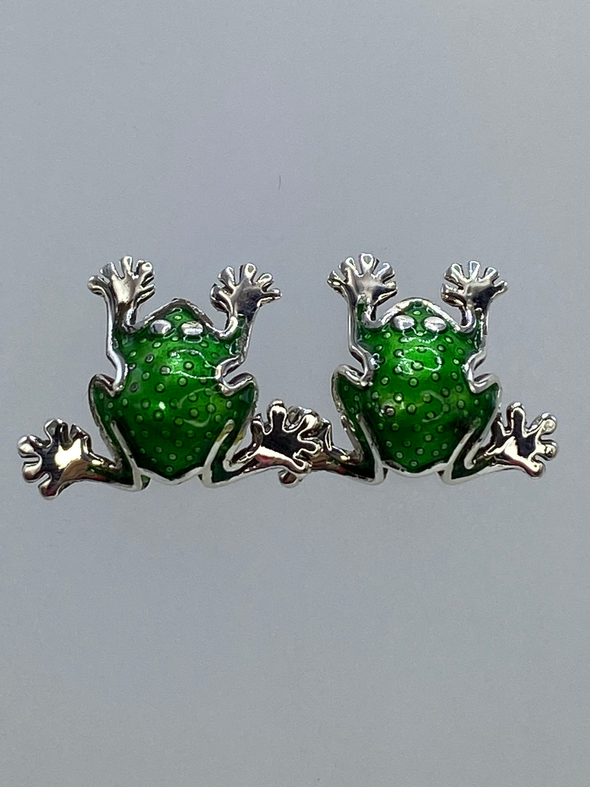 Par de aretes de plata en forma de ranita con repujado volumétrico, vista frontal