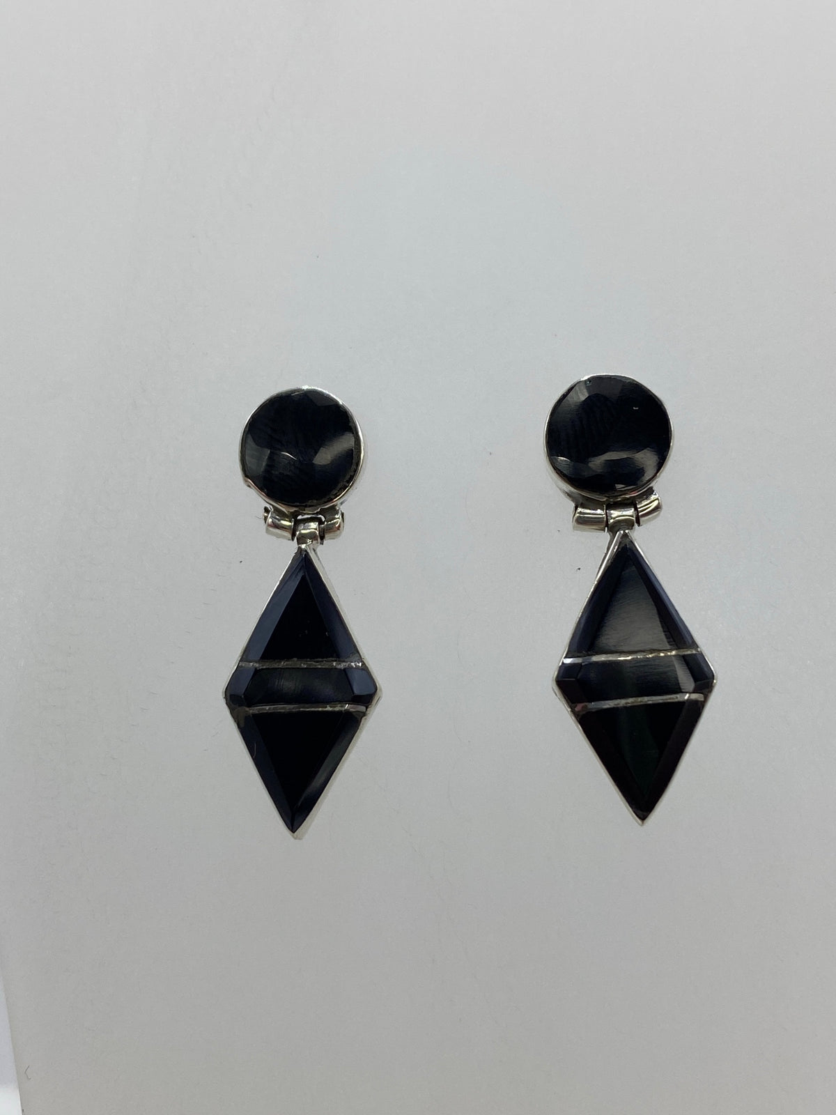 Aretes de plata 950 con ónix negro sobre fondo gris, detalle del engaste a mano