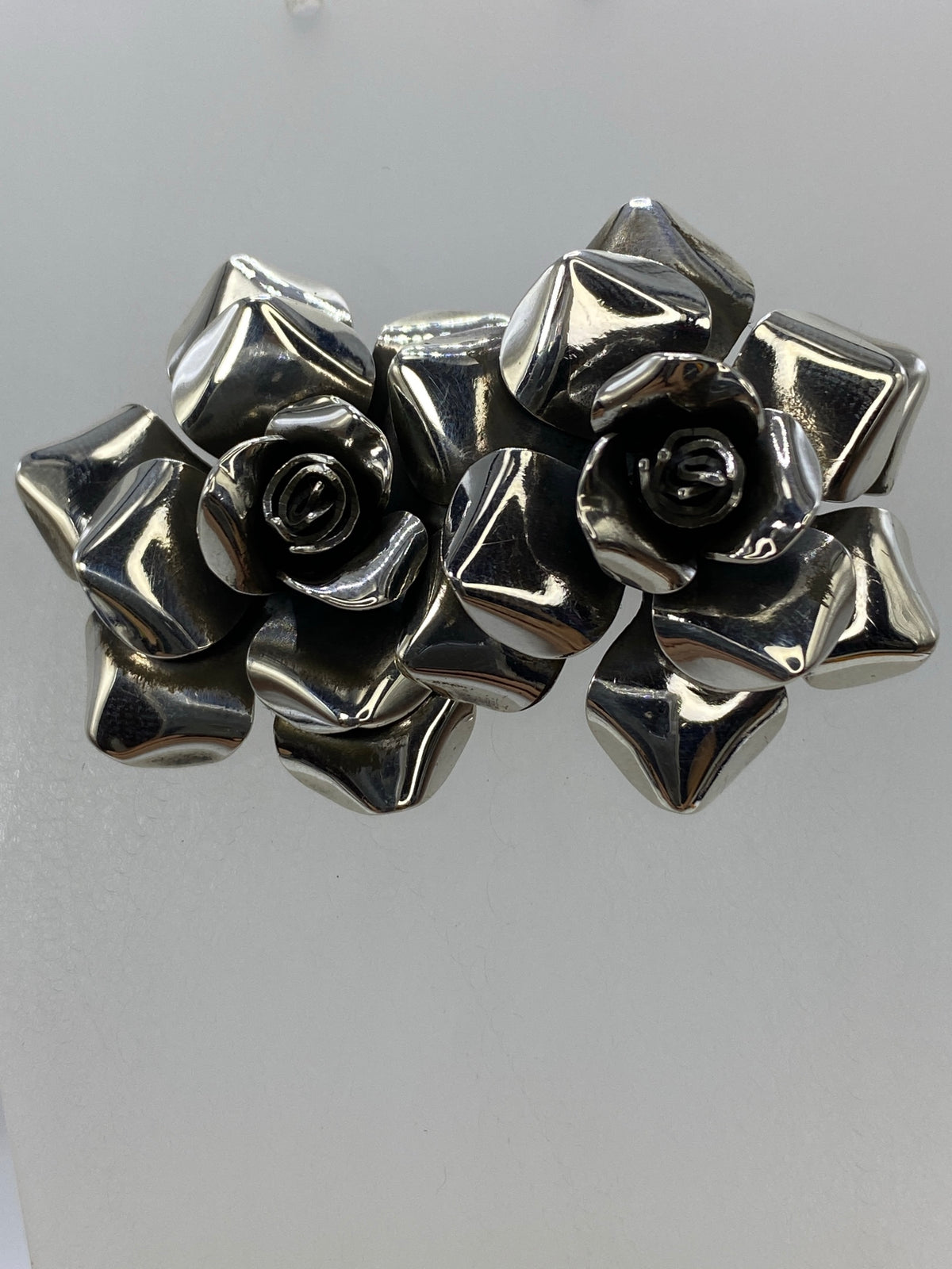 Aretes de plata con flores en relieve, mostrando los pétalos martillados a mano