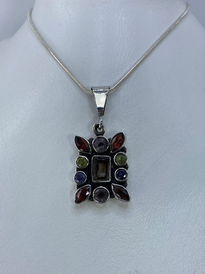 Vista frontal del dije de plata 925 con circonia roja, morada, verde y amarilla