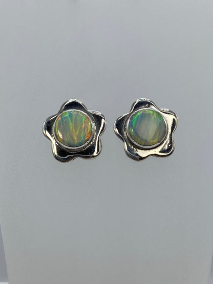 Detalle frontal de los aretes mostrando el juego de colores verde, oro y naranja del ópalo