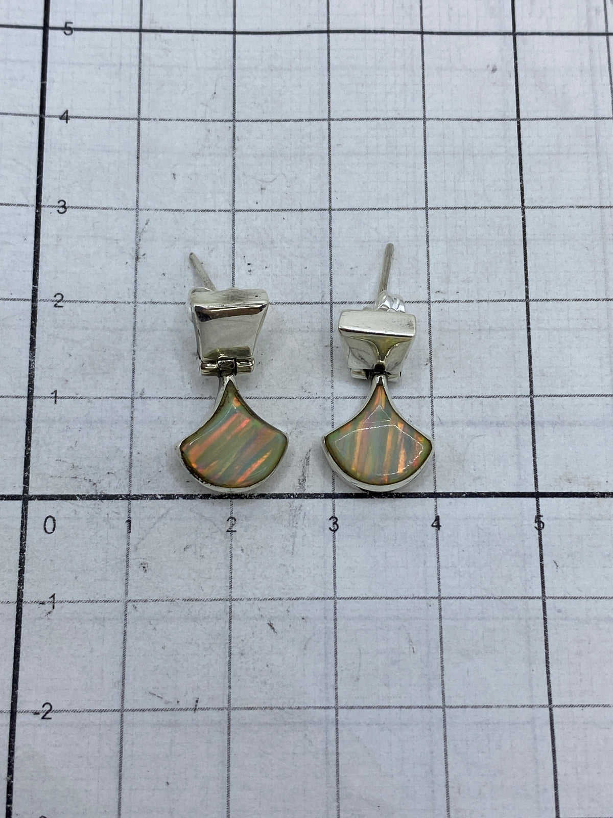Aretes puestos mostrando el brillo multicolor del ópalo de fuego en Taxco 925