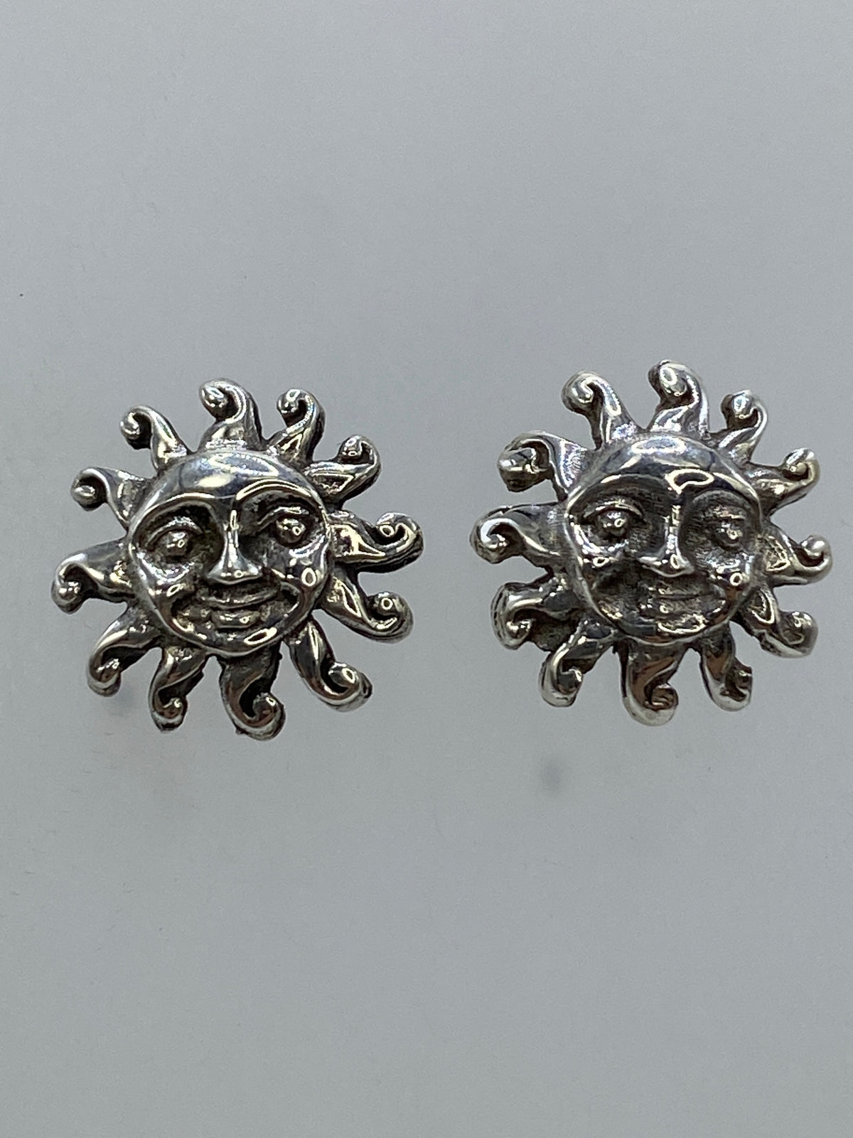 Par de aretes de plata con motivo de sol sonriente fundido, vista frontal