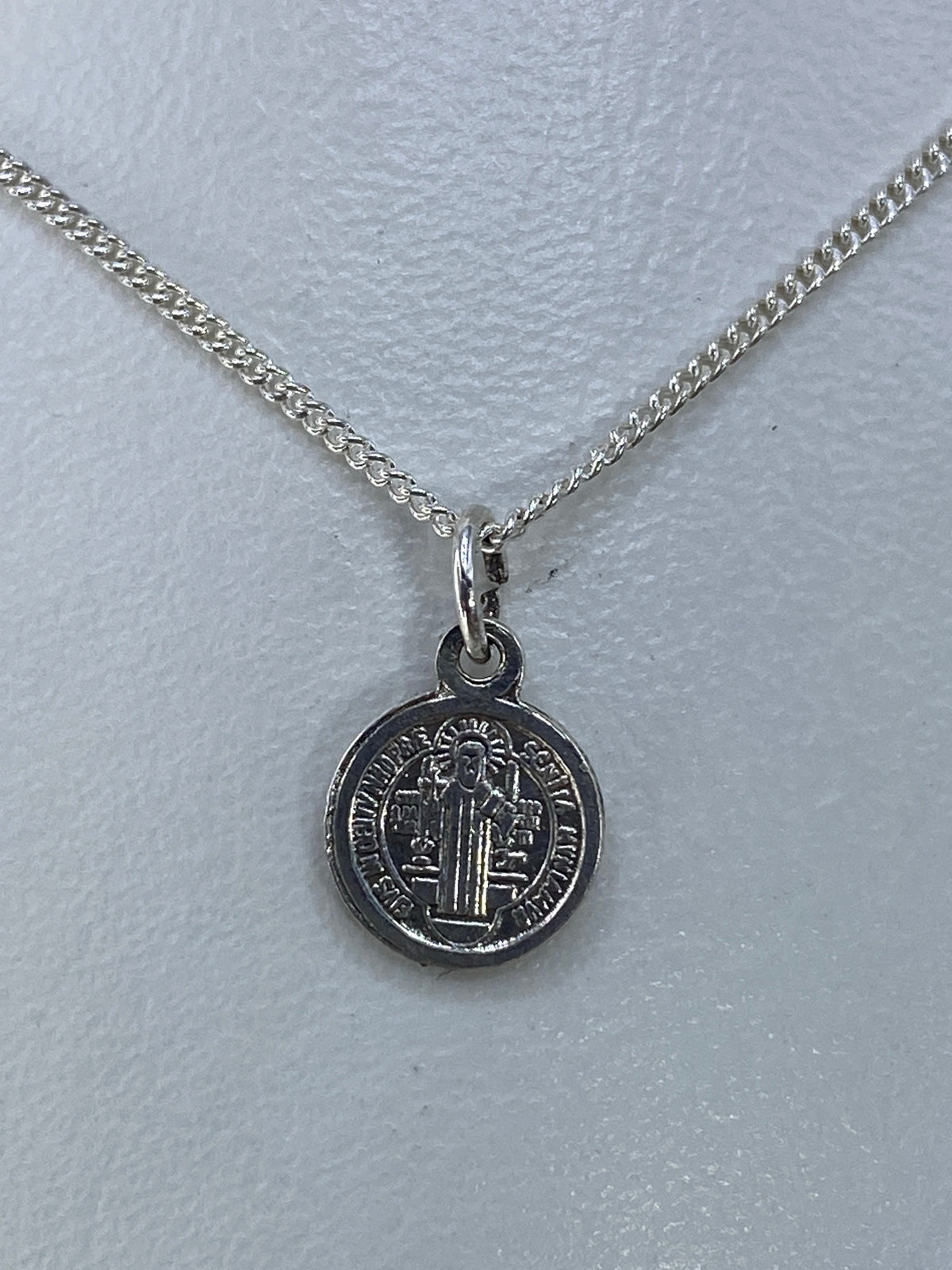Reverso del dije de San Benito con inscripción y cruces grabadas en plata