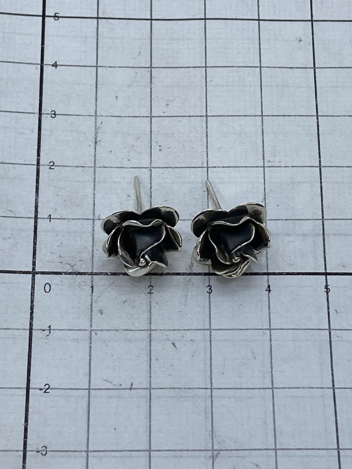 Aretes de rosa de Taxco sobre fondo azul con sello 925 visible