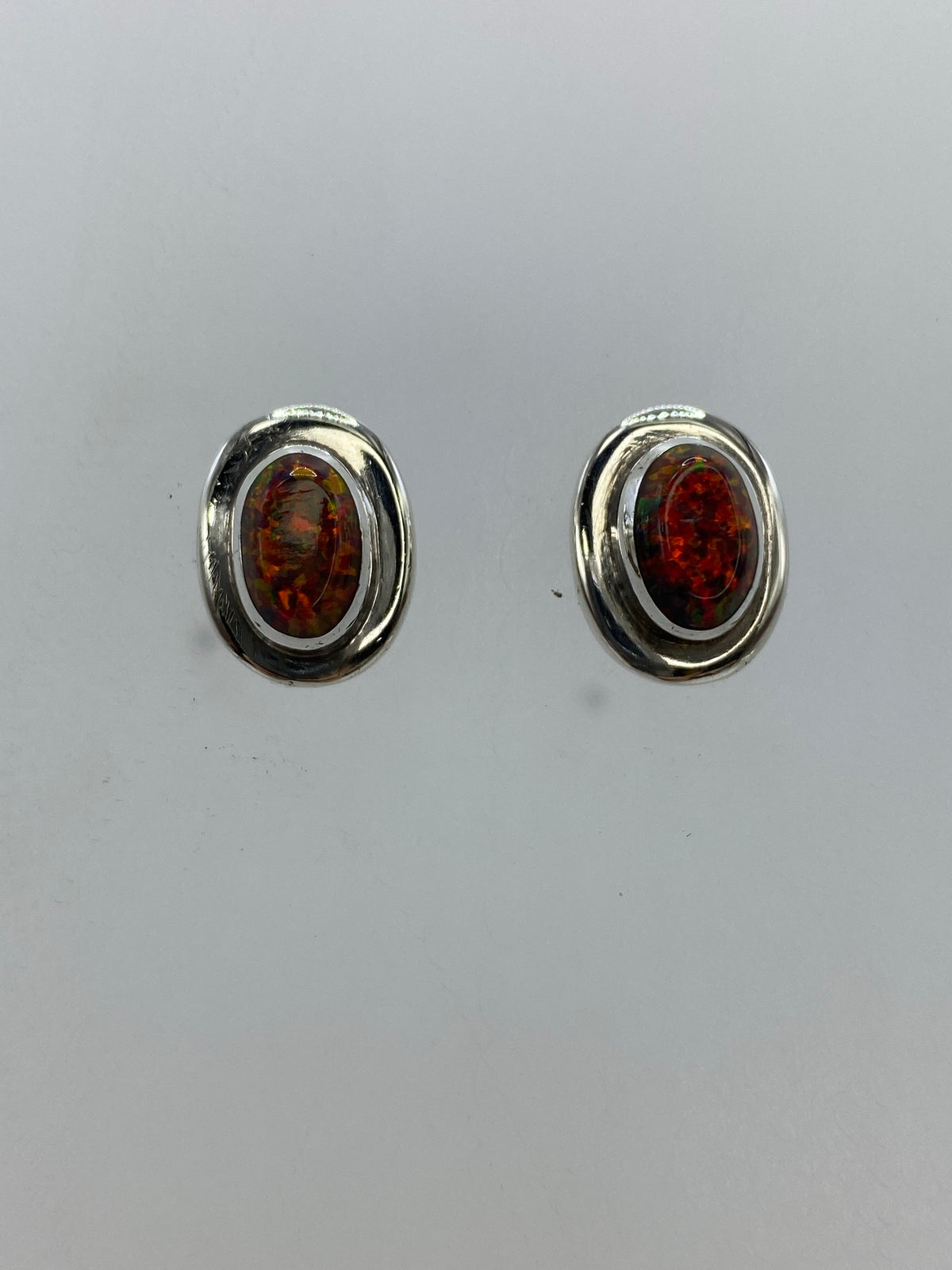 Detalle frontal de un arete mostrando el fuego y los reflejos del ópalo multicolor