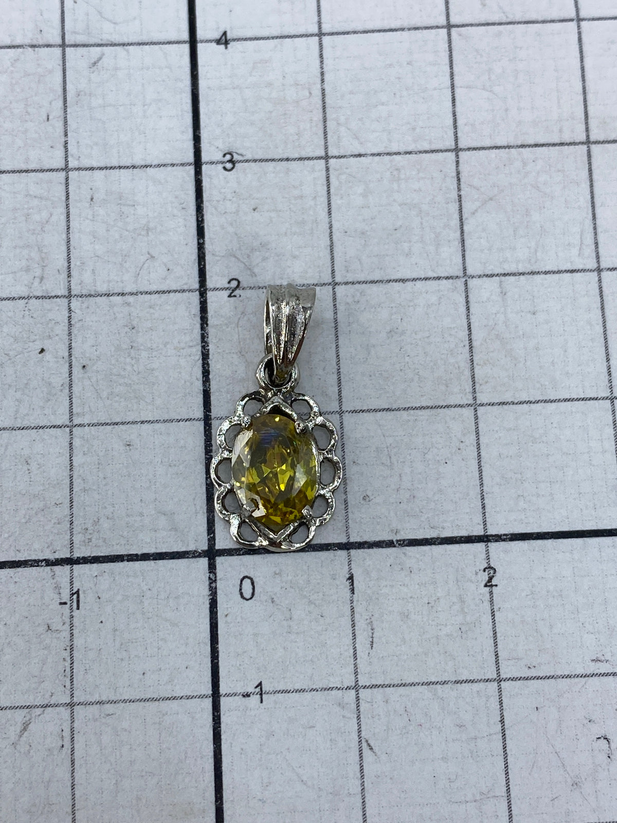 Dije de plata en fondo blanco mostrando el brillo de la circonia amarillo