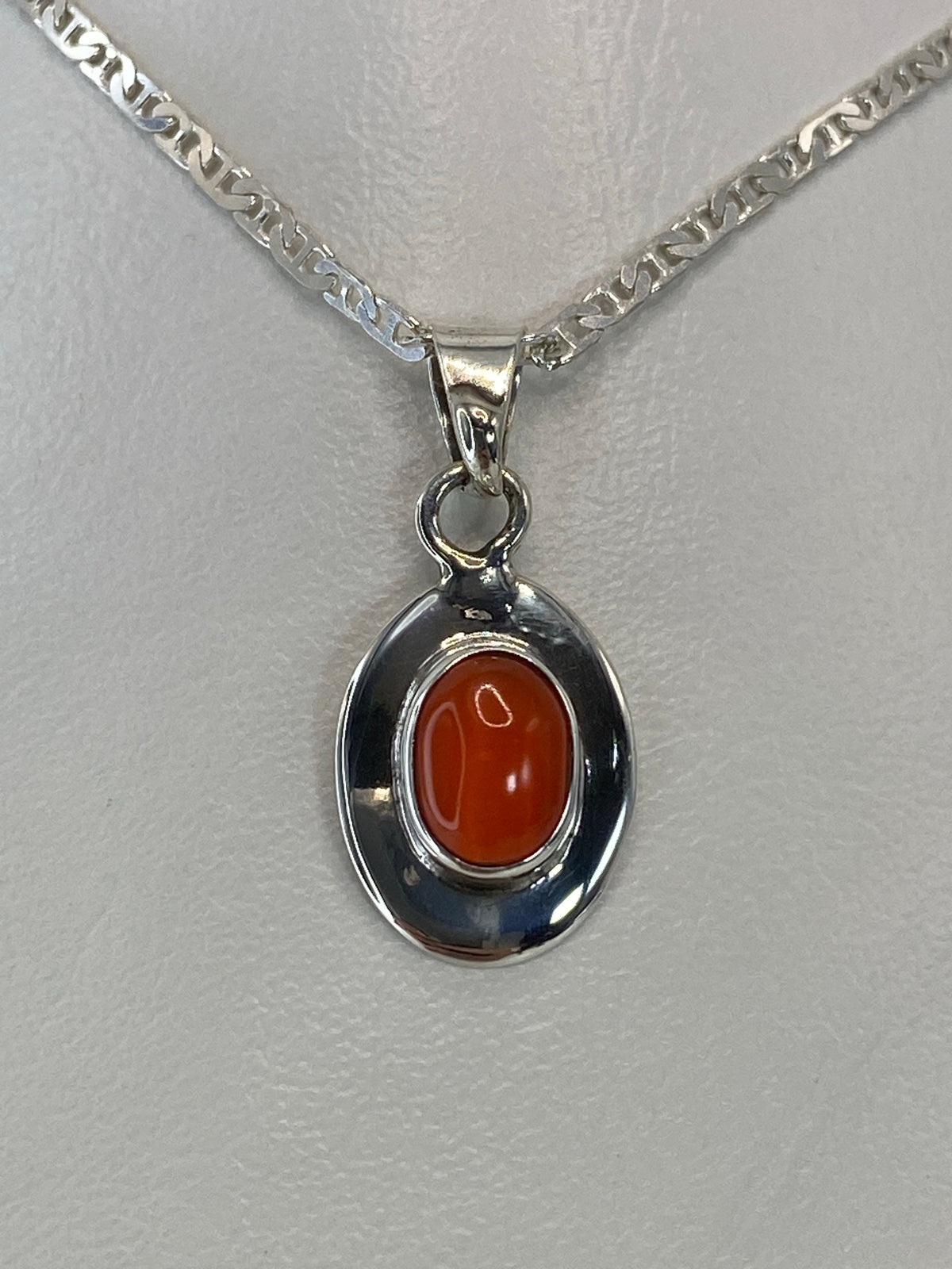 Vista frontal del dije compacto de 2.3 cm con piedra naranja engastada