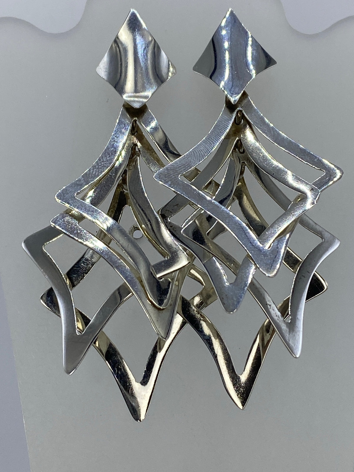 Aretes de plata calado geométrico escalonado, vistos de frente mostrando el diseño de capas