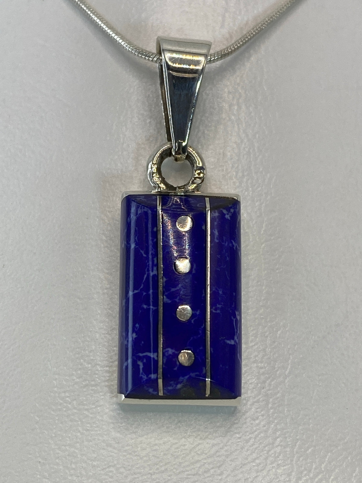 Dije de plata 925 con piedra azul engastada, colgando de cadena plateada