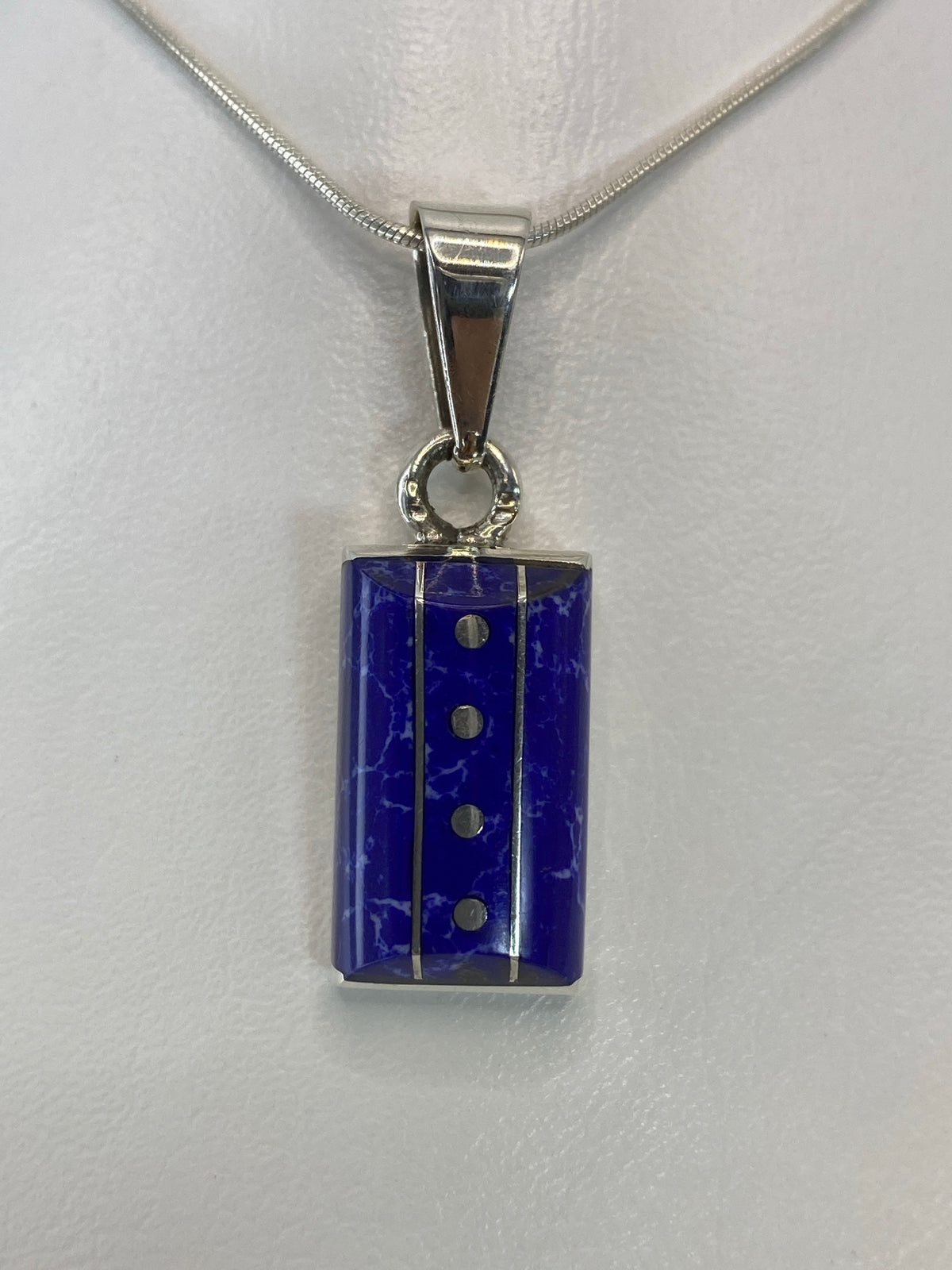 Vista frontal del dije rectangular de 3.7 cm con piedra azul y líneas de filigrana