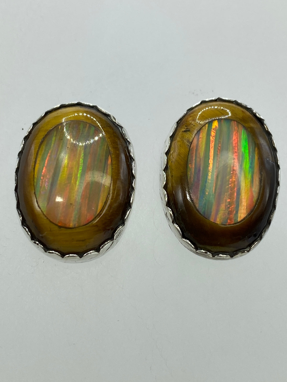Aretes puestos, mostrando los destellos del opalo de fuego y la línea de luz del ojo de gato