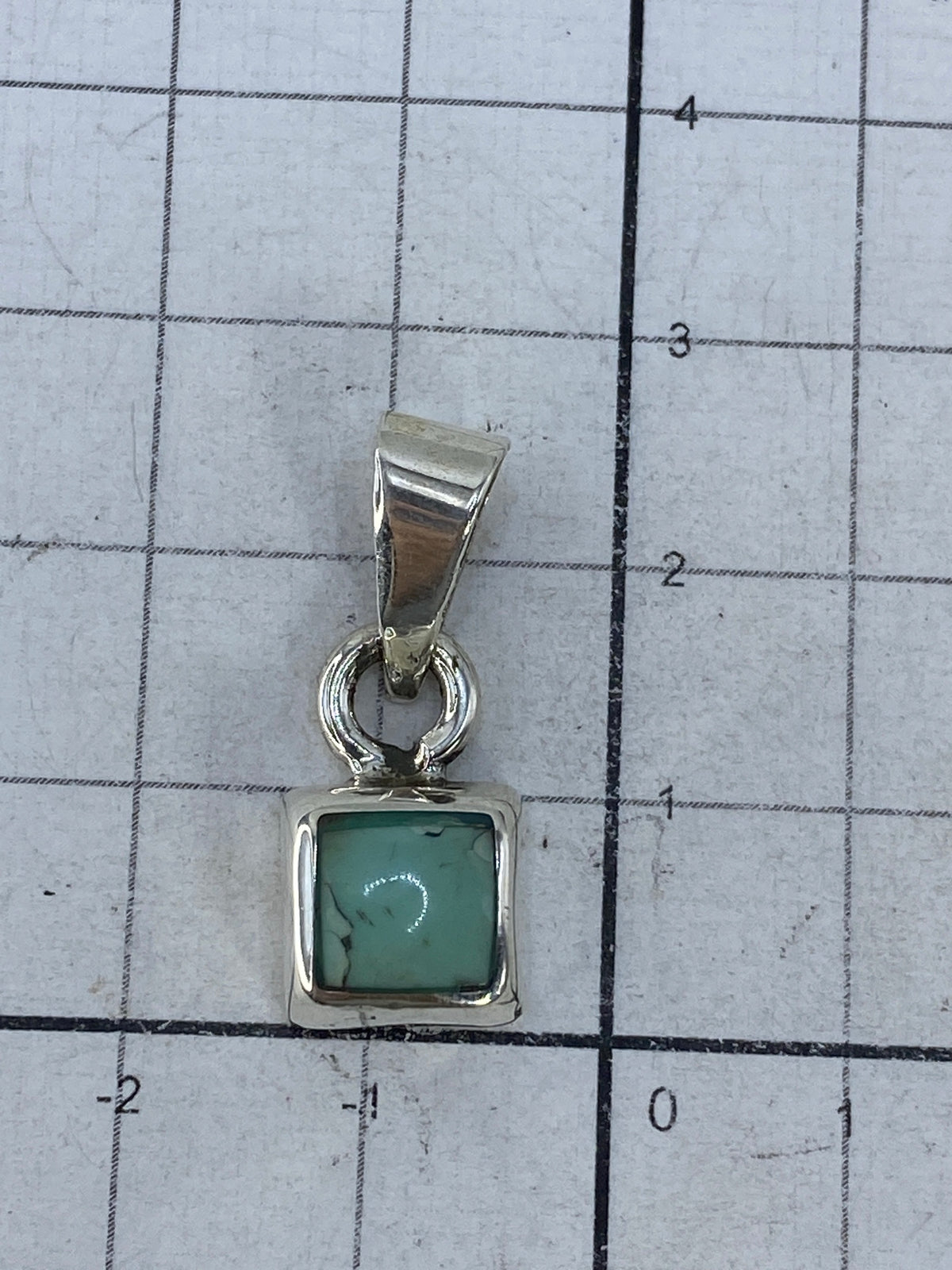 Dije de plata en balanza mostrando peso de 4.16 gramos
