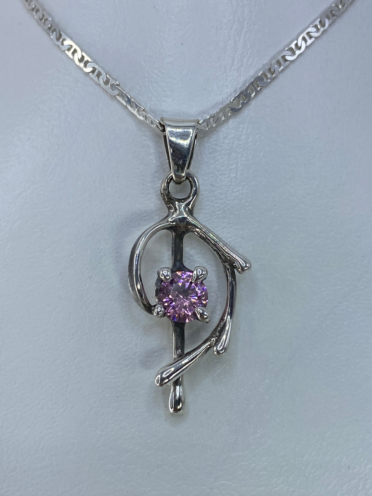 Detalle del dije mostrando la circonia rosa engastada a mano en plata pulida