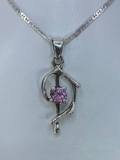 Detalle del dije mostrando la circonia rosa engastada a mano en plata pulida