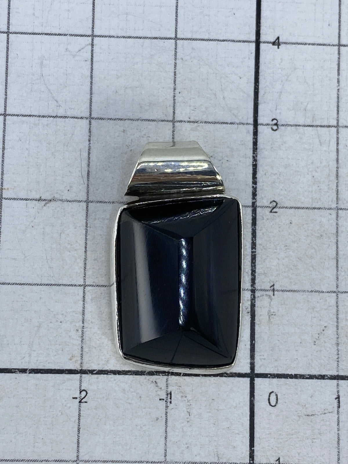 Dije sobre collar de plata para referencia de tamaño y proporción