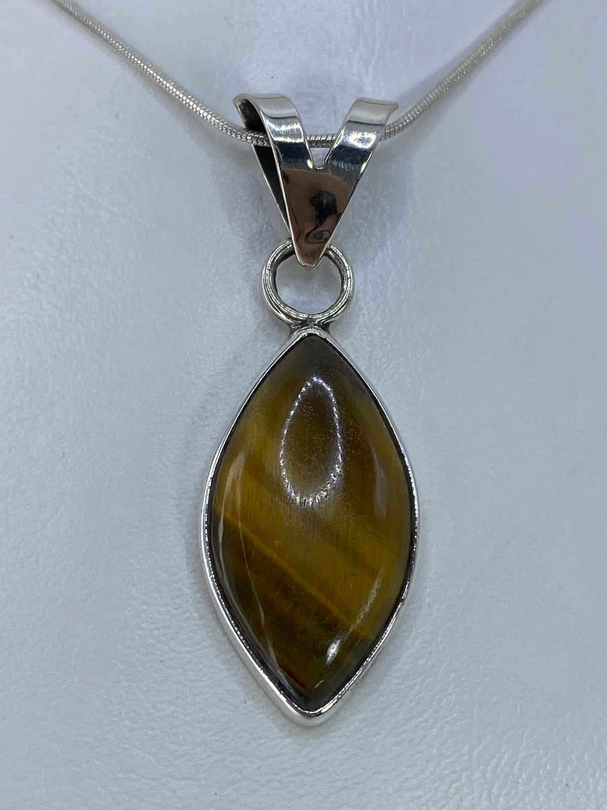 Dije ovalado de plata 925 con Ojo de Tigre café, engastado con aro de plata, sobre cadena serpentina plateada