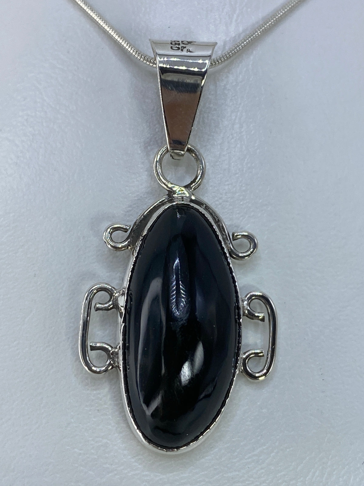 Dije de plata 950 con onix negro engastado en marco de espiral plateado